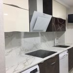 En este caso estamos con la gama de marrones, poniendo en la zona de abajo un marrón oxido en mate y en la zona de arriba un beige brillo, con encimera de Dekton mezclando tonos en marrón y frontal forrado del mismo material que encimera, en este caso el tirador es lengueta.